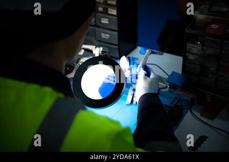 Le technicien doit utiliser des lumières vives et une loupe pour vérifier les détails de la pièce. Impression de l'imprimante 3D. Banque D'Images