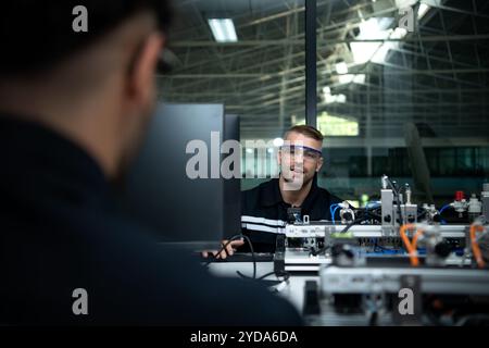 Le professeur de technologie de la main robotisée enseigne aux nouveaux étudiants comment utiliser les cartes de circuits électroniques et la commande manuelle robotisée Banque D'Images