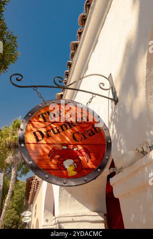 Panneau orange extérieur suspendu à un bâtiment en stuc blanc pour le restaurant Drunken Crab sur State Street à Santa Barbara, Californie. Banque D'Images