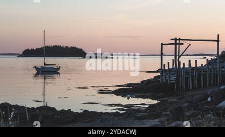 Coucher de soleil rose reflet avec voilier et jetée de pêche rustique à Stonington Maine sur Deer Isle Banque D'Images