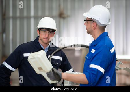 Les deux ingénieurs vérifient le fonctionnement des robots de soudage. Banque D'Images