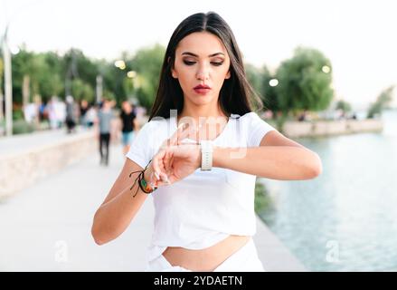 femme vérifiant son activité physique sur smartwatch. Jeune athlète féminine regardant sur le tracker d'activité pendant l'entraînement. Banque D'Images