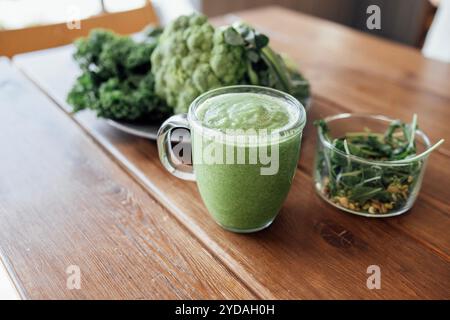 Gros plan du smoothie vert d'un blender dans une tasse en verre sur la table de la cuisine Banque D'Images