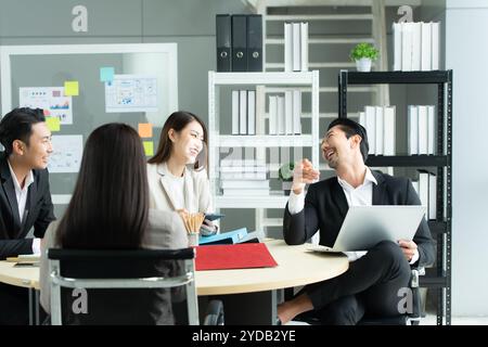 Un groupe de jeunes entrepreneurs asiatiques. La haute direction se réunit pour examiner les données d'investissement boursier de l'équipe dans une salle de réunion Banque D'Images