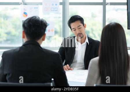 Un groupe de jeunes entrepreneurs asiatiques. La haute direction se réunit pour examiner les données d'investissement boursier de l'équipe dans une salle de réunion Banque D'Images