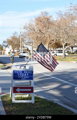 Venise, Floride, États-Unis – 24 octobre 2024 : drapeau américain et tableau sandwich indiquant « votez ici aujourd'hui » avec une flèche pointant vers le lieu de vote. Banque D'Images