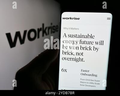 Dans cette illustration photo, une personne tenant un téléphone portable avec le site Web de la société américaine de logiciels Workrise technologies Inc devant le logo. Banque D'Images