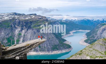 Deux randonneurs se tiennent au bord de Trolltunga, en Norvège, une falaise massive surplombant un magnifique fjord en Norvège. L'immensité du paysage et le shee Banque D'Images