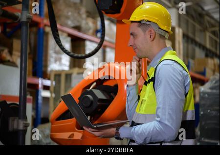 Un ingénieur vérifiant le fonctionnement d'un robot de soudage. Utilisé pour le contrôle de soudage de précision rapide et hautement sécurisé Banque D'Images