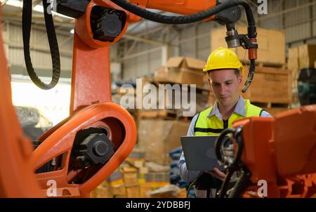 Un ingénieur vérifiant le fonctionnement d'un robot de soudage. Utilisé pour le contrôle de soudage de précision rapide et hautement sécurisé Banque D'Images