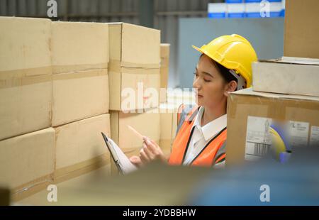 Travailleuse d'entrepôt comptant des articles dans un entrepôt industriel sur le plancher de mezzanine de l'usine. ce qui est un stockage pour les petits Banque D'Images