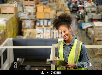 Travailleuse d'entrepôt comptant des articles dans un entrepôt industriel sur le plancher de mezzanine de l'usine. ce qui est un stockage pour les petits Banque D'Images