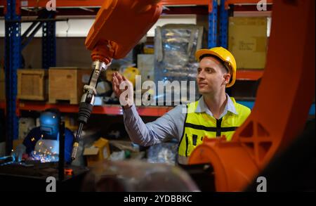 Un ingénieur vérifiant le fonctionnement d'un robot de soudage. Utilisé pour le contrôle de soudage de précision rapide et hautement sécurisé Banque D'Images