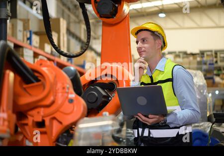 Un ingénieur vérifiant le fonctionnement d'un robot de soudage. Utilisé pour le contrôle de soudage de précision rapide et hautement sécurisé Banque D'Images