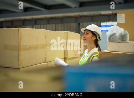 Travailleuse d'entrepôt comptant des articles dans un entrepôt industriel sur le plancher de mezzanine de l'usine. ce qui est un stockage pour les petits Banque D'Images