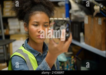 Travailleuse d'entrepôt comptant des articles dans un entrepôt industriel sur le plancher de mezzanine de l'usine. ce qui est un stockage pour les petits Banque D'Images