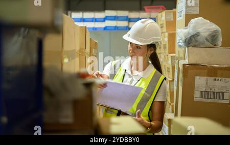 Travailleuse d'entrepôt comptant des articles dans un entrepôt industriel sur le plancher de mezzanine de l'usine. ce qui est un stockage pour les petits Banque D'Images