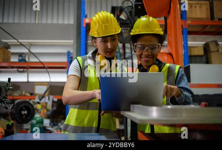 Deux femmes ingénieur vérifiant le fonctionnement d'un robot de soudage. Utilisé pour le contrôle de soudage de précision rapide et hautement sécurisé Banque D'Images