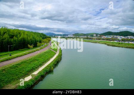 Ulsan, Corée du Sud - 5 octobre 2024 : une vue en amont de la rivière Taehwagang, avec un sentier riverain bordé de forêts de bambous. Le paysage urbain d'Ulsan Banque D'Images