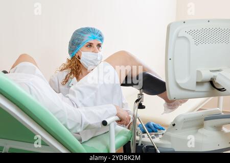 Gynécologue examinant un patient assis sur une chaise gynécologique Banque D'Images