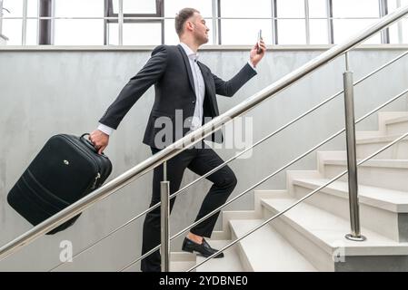 Homme d'affaires tenant une valise dans un bâtiment moderne Banque D'Images