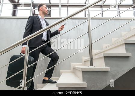 Homme d'affaires tenant une valise dans un bâtiment moderne Banque D'Images
