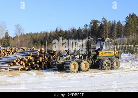 Transporteur forestier Ponsse Wise avec chaînes à neige sur pneus et grumes de pin empilées sur le chantier en hiver. Salo, Finlande. 9 février 2024 Banque D'Images