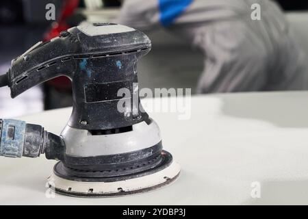 Auto mécanicien polissage et voiture de polissage dans l'atelier de réparation automobile avec polisseur orbital, nettoyage de couche de base Banque D'Images