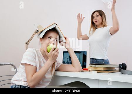 Mère et fille se battant pour les devoirs, la mère bouleversée est en colère contre la petite fille ennuyeuse, homeschooling, malentendu Banque D'Images