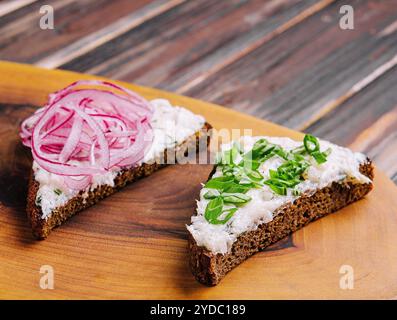 Morceaux de pain avec délicieux saindoux avec des oignons rouges et verts Banque D'Images