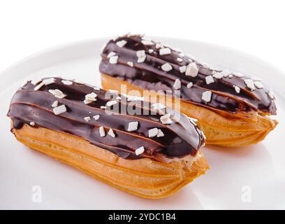 Deux eclairs avec glaçage au chocolat dans une assiette blanche Banque D'Images