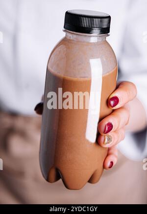 Femme tenant des smoothies au chocolat dans des bouteilles en plastique Banque D'Images