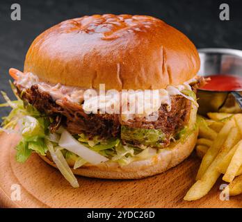 Délicieux hamburger avec sauce au fromage et frites sur une table en bois Banque D'Images