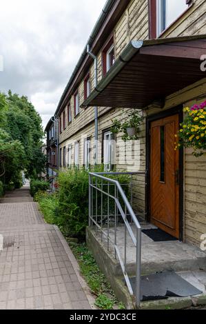 Tukums, Lettonie - 22 août 2024 : une passerelle entourée de verdure avec des bâtiments des deux côtés. Banque D'Images