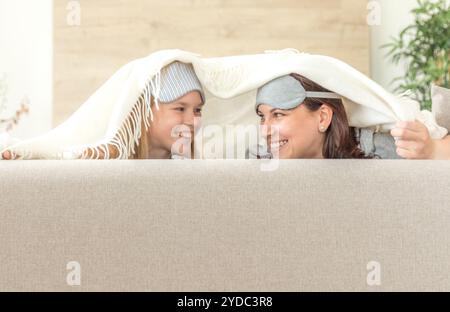 Mère et fille portant un masque de sommeil s'amusant sur la table dans la salle de séjour Banque D'Images