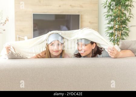 Mère et fille happ concept famille. Le port de masque de sommeil et s'amuser sur sofa in living room with copy space Banque D'Images