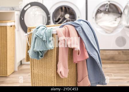 Panier à linge avec des vêtements sales avec les machines de lavage et de séchage sur l'arrière-plan Banque D'Images