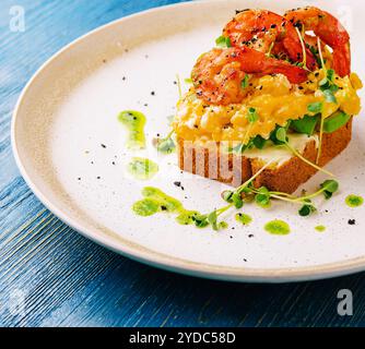 Oeufs brouillés avec avocat et crevettes sur assiette Banque D'Images