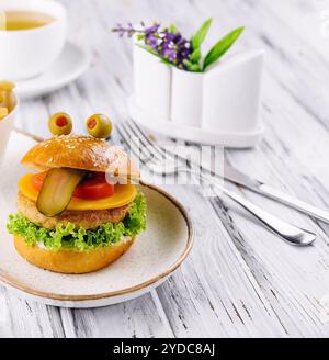Mini hamburger montre la langue. Le concept d'un hamburger préféré des enfants. Banque D'Images