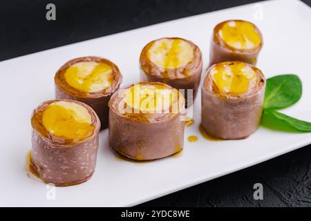 Rouleaux de crêpes à la banane au chocolat sur assiette blanche Banque D'Images