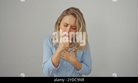 Une jeune femme dans une chemise bleue toussant dans son poing sur un fond blanc Banque D'Images