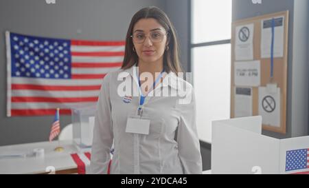 Une jeune femme hispanique avec des lunettes, portant un autocollant «j'ai voté», pose dans un centre de vote d'un collège électoral américain. Banque D'Images