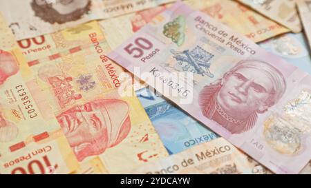 Billets de banque mexicains éparpillés avec diverses coupures montrant les dessins complexes et les couleurs vibrantes de la monnaie pesos au mexique Banque D'Images