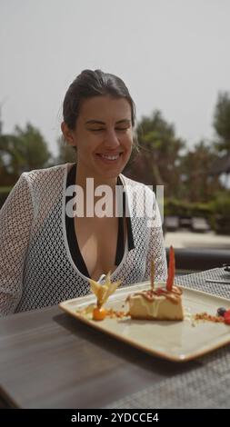 Femme hispanique célébrant son anniversaire avec un gâteau sur la terrasse d'un restaurant balinais extérieur. Banque D'Images
