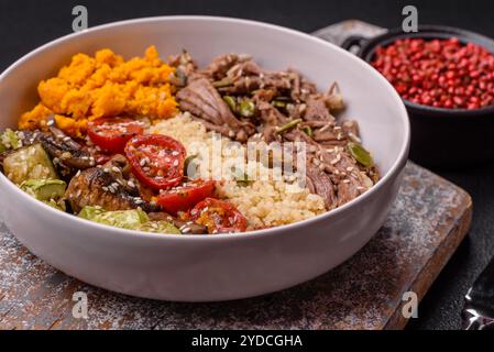 Bol de nourriture avec boeuf, bulgur, tomates, champignons, courgettes et sauce. Plat végétalien Banque D'Images