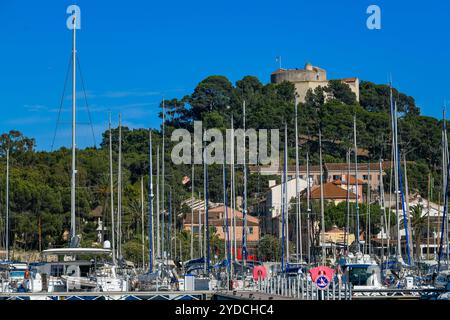 France, Porquerolles, 9 juin 2024 : bateaux dans le port de l'île de Porquerolles, et Fort Sainte Agathe Banque D'Images