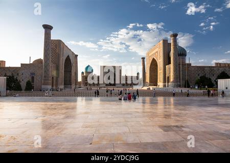 Samarcande, Ouzbékistan - 05 juillet 2024 : les trois portails avec leurs madrasas sur la place Registan de Samarcande au coucher du soleil et les touristes Banque D'Images