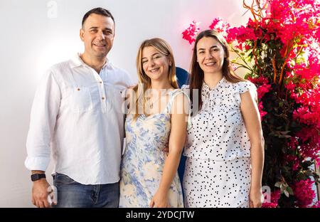 Une adolescente mignonne et ses parents dans des vêtements de fantaisie sourient et posent. Une jeune fille joyeuse, son père et sa mère s'embrassent lors d'une réunion festive. Un homme et une femme wi Banque D'Images