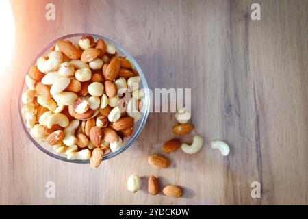 Noix de cajou, cacahuètes et amandes sur une assiette. Noix sur la table dans les rayons lumineux du soleil.. Banque D'Images