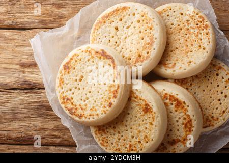 Délicieuses crumpets anglaises chaudes ou gros plan de pain poreux sur une planche de bois sur la table. Vue horizontale de dessus Banque D'Images